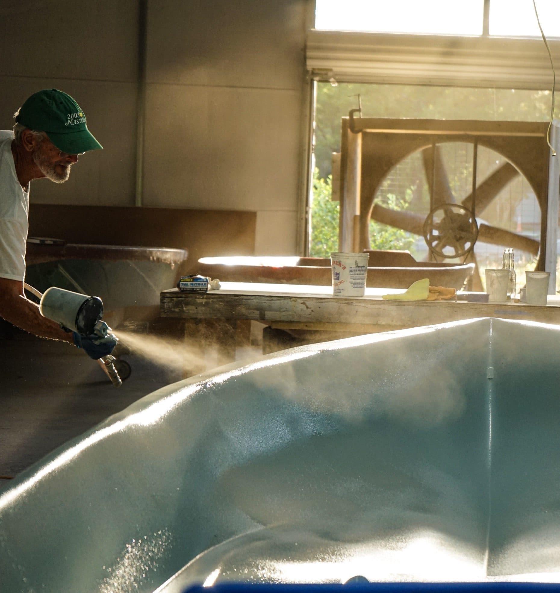 Harry Spear spraying gel coat into a hull mold in his shop
